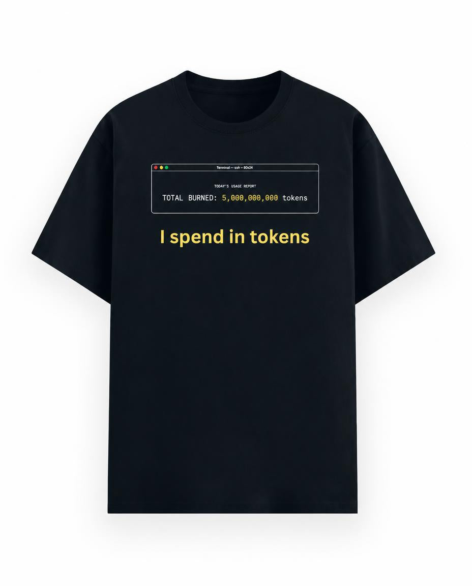 A navy blue short-sleeve t-shirt with a graphic print on the chest. The graphic features a computer window with white text reading 'TOTAL BURNED: 5,000,000,000 tokens' and the phrase 'I spend in tokens' printed below in yellow.