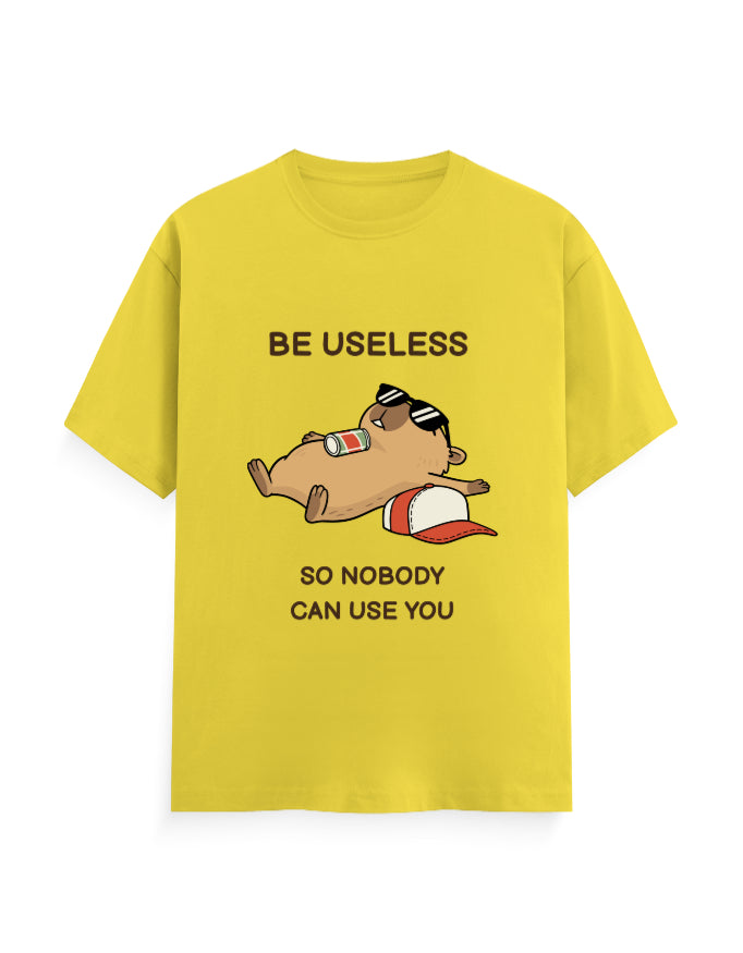 A bright yellow short-sleeve t-shirt with a cartoon graphic of a sleeping beagle wearing sunglasses and a red-and-white cap, accompanied by the text 'BE USELESS SO NOBODY CAN USE YOU'.