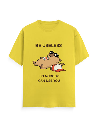 A bright yellow short-sleeve t-shirt with a cartoon graphic of a sleeping beagle wearing sunglasses and a red-and-white cap, accompanied by the text 'BE USELESS SO NOBODY CAN USE YOU'.