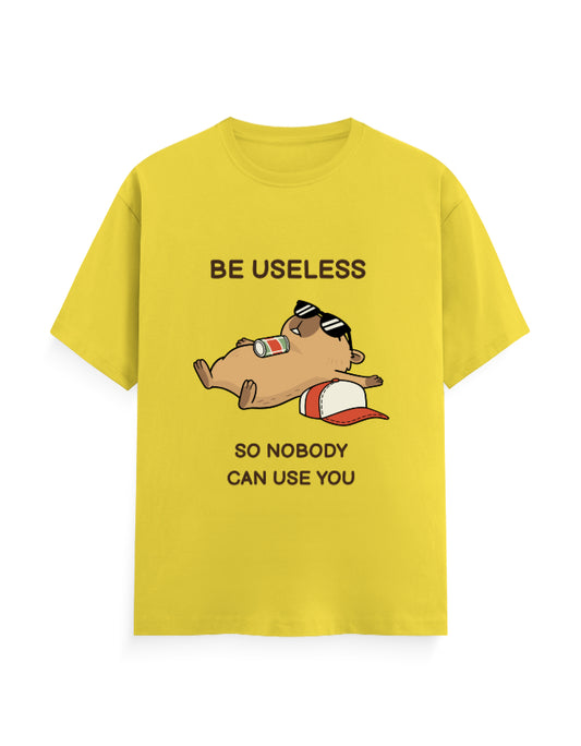 A bright yellow short-sleeve t-shirt with a cartoon graphic of a sleeping beagle wearing sunglasses and a red-and-white cap, accompanied by the text 'BE USELESS SO NOBODY CAN USE YOU'.